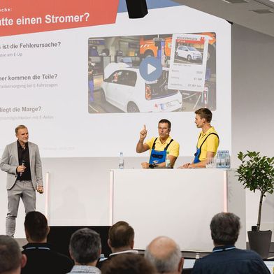 Klare Ansage von der Bühne: Holger Parsch (mit erhobenem Zeigefinger), Robin Schürer und Produzent Lars Faust von den VOX-„Autodoktoren" appellierten an die Werkstätten, sich mit der E-Mobilität zu beschäftigen. (Bild: Stefan Bausewein)