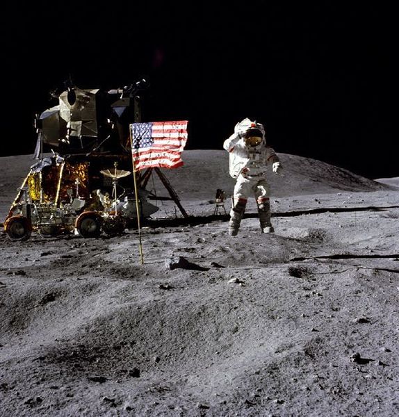 Apollo-16-Kommandant John W. Young bei einem Sprung während er vor der US-Flagge salutiert. Links im Bild zu sehen sind das Landemodul „Orion“ und der Rover (Bild: NASA)