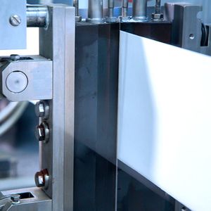 Hier sieht man, wie eine zuvor per Laser aktivierte Papierbahn durch das sogenannte Wärmekontakt-Siegelverfahren verschlossen wird. Zuckerartige Spaltprodukte, die zuvor mittels Laserbestrahlung erzeugt wurden, machen das ohne Klebstoffe möglich.(Bild:  Fraunhofer IVV)