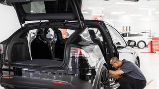 Ein Mitarbeiter eines Tesla-Centers an einem Model X. (Tesla)