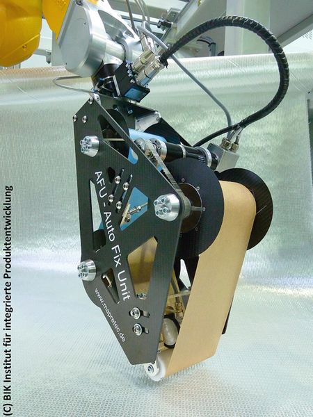 Roboter unterstützt Roboter	 Die Bindereinheit kann als Werkzeug an einen Knickarmroboter gekoppelt werden, der kopfüber hängend von einem Portalroboter geführt wird. So erreicht das System auch schwer zugängliche Bereiche. (Bild: BIK)