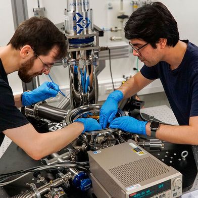 David Walther (links) und Carlos Rincon, wissenschaftliche Mitarbeiter am Lehrstuhl für Werkstoffe und Zuverlässigkeit mikrotechnischer Systeme der Technischen Universität Chemnitz, installieren einen neuen Prüfstand im Inneren der Kammer eines Helium-Kryostaten. (Bild: TU Chemnitz)