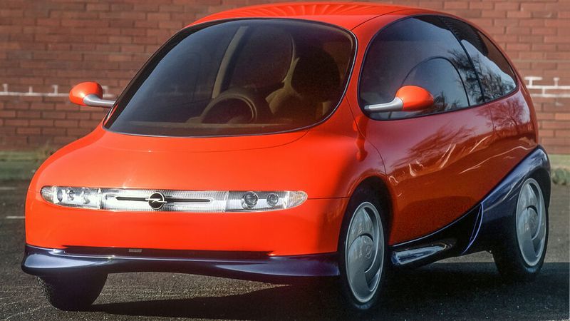 1992 präsentierte Opel die Zukunftsstudie „Twin“ mit zwei Radnabenmotoren für  emissionsfreien innerstädtischen Verkehr. Bei dem Elektroauto kann die Antriebseinheit, d. h. der Akkumulator und der Elektromotor, für Langstrecken durch ein Antriebsmodul mit herkömmlichem Dreizylinder-Verbrennungsmotor ausgetauscht werden kann. Das Austauschmodul beinhaltet neben dem jeweiligen Motor und dem nötigen Energiespeicher auch die Hinterachse und die Hinterräder.  (Bild: Opel / Stellantis)