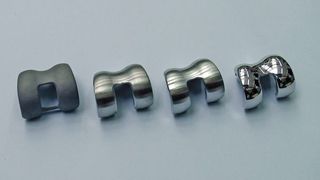 Bild 1: Dieses Oberteil eines Kniegelenkimplantats wurde in vier Stufen hergestellt – (v.l.n.r.) Feingießen, Geometrieschleifen, Feinschleifen und Hochglanzpolieren. Die beiden letzten Prozesse fanden im Schleppfinish-Verfahren statt. Bild: Rösler (Archiv: Vogel Business Media)