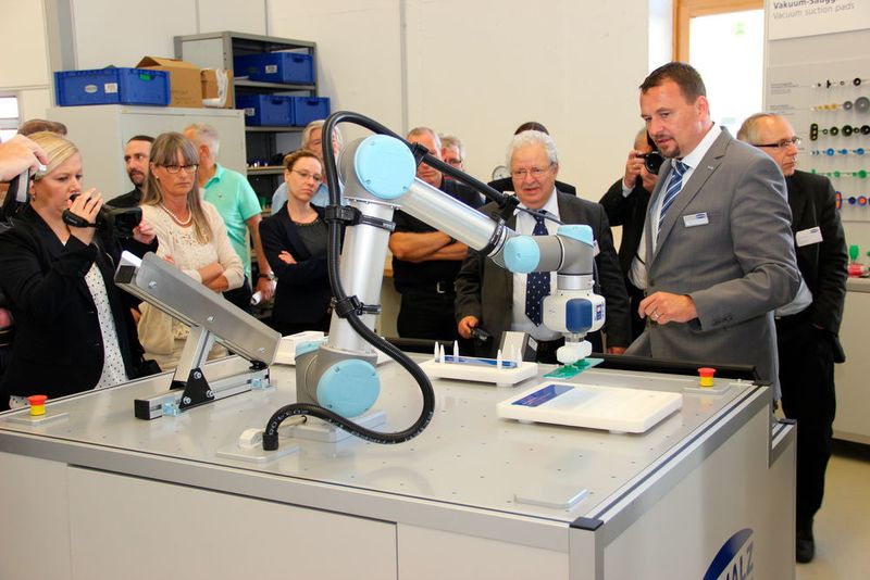 Walter Dunkmann (rechts im grauen Anzug) verantwortet das Geschäftsfeld Vakuum-Automation. Hier erklärt er den Anwesenden, wie sich mittels Near Field Communication, kurz: NFC, Service- und Wartungsinformationen aus einer Anwendung herausziehen lassen. (Gillhuber)