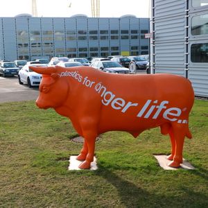 Offizielles Firmenmotto: Der große Kunststoff-Bulle bewacht das Produktionsgebäude, in Firmenfarbe und dem Spruch „plastics for longer life“ auf dem breiten Rücken. 