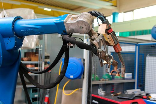 Will man beim MAG-Schweißen möglichst witschaftlich sein, sollte man die Bauteile vorwärmen. Vorversuche bei TIME nutzen hierzu einen Induktorkopf unmittelbar vor dem MAG-Brenner. Der Kopf erwärmt das Werkstück unmittelbar vor dem eigentlichen Schweißvorgang lokal auf.(Bild:  TIME)