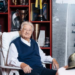 Hans Herrmann vor der Sammlung seiner Pokale, aufgenommen 2022. Fast 50 Jahre lang (bis Juli 2016) betrieb Herrmann den Zubehörhandel Hans Herrmann Autotechnik und war Mitglied der Jury „Das Goldene Lenkrad“. 2013 wurde ihm der Béla-Barényi-Preis verliehen. (Bild:  Mercedes-Benz AG)