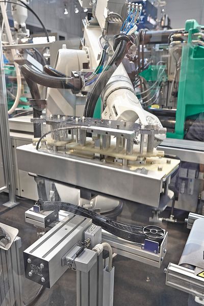 Der Sechs-Achs-Roboter legt die Fertigteile in eine Station zur Druck- und Festigkeitsprüfung ab, bevor sie das Förderband als Gutteile aus der Anlage ausschleust. (Bild: Arburg)