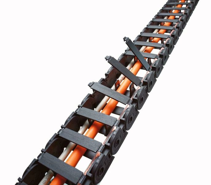 Quicktrax Energieführungsketten besitzen Verschlussbügel mit flexiblem Filmscharnier, die sich bei leichtem Druck auf den Entriegelungsmechanismus nahezu von selbst öffnen. (Tsubaki Kabelschlepp)
