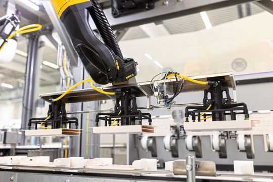 A six-axis robot erects cardboard inlays. A six-axis robot erects cardboard inlays.