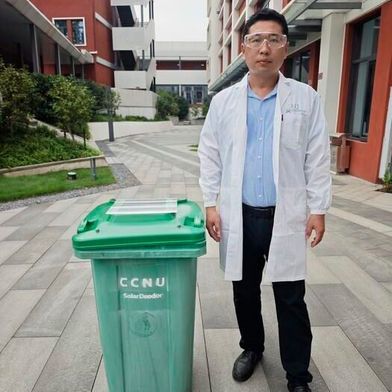 Researcher Jinlong Wang stands beside a garbage bin fitted with a solar-powered insert on the lid that efficiently removes food waste smells compared to a garbage bin with a typical lid.  (Source: Pan Yan)