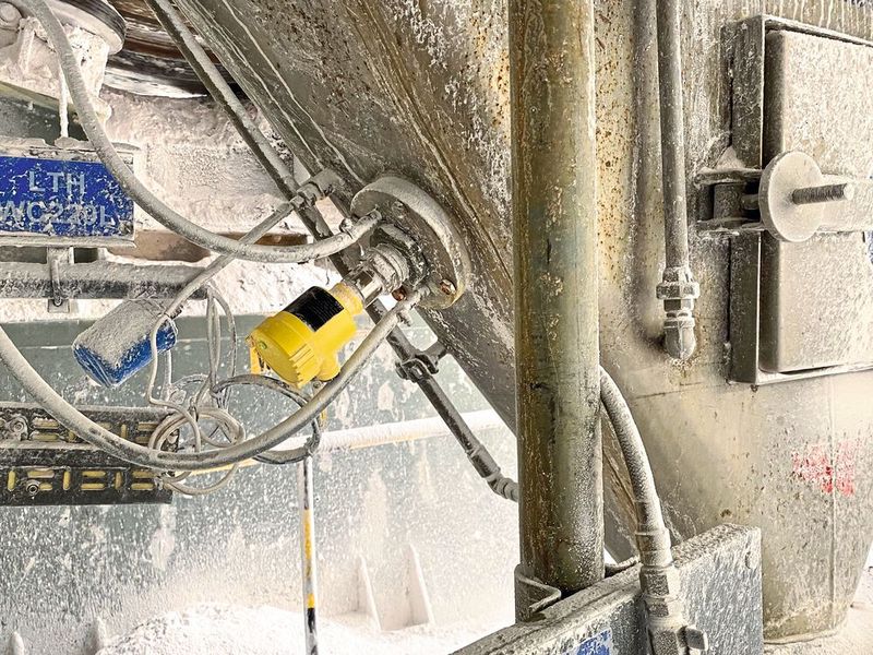 Der Vegacap 65 auf einem Aufnahmetrichter: Selbst von starken Pulver-Anhaftungen, die sich rund um den Sensor bilden, bleibt die Messung unbeeinflusst. (Bild: Vega Grieshaber)