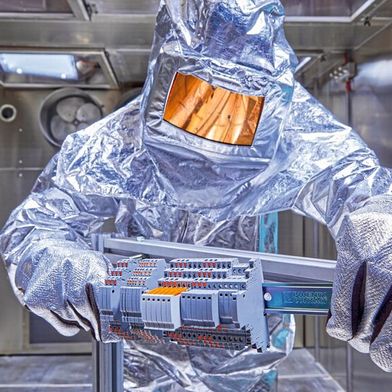Ein Mitarbeiter von NMi Testlab entnimmt eine elektrische Baugruppe aus einer thermischen Prüfkammer. Der Hitzeschutzanzug schützt ihn beim Umgang mit dem Prüfling unter hohen Temperaturen. (Bild: NMI Testlab)