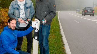Die Studenten Benjamin Kirsch (kniend), Julian Neu (Mitte) und Daniel Gillo (r.) haben ein solarbetriebenes Sensorsystem entwickelt, das Falschfahrer früh erkennt und Warnungen veranlassen kann. (Oliver Dietze / Saar Uni)