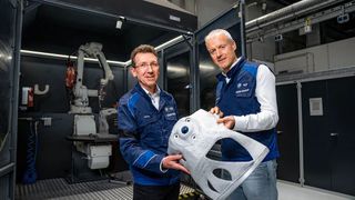 Zwei Spezialisten der BMW Group präsentieren hier ein Aluminiumbauteil, dass durch das additive Fertigungsverfahren Wire Arc Additive Manufacturing (WAAM) hergestellt wurde. Es konnte gezeigt werden, dass die Herstellung im Vergleich zum Druckguss Ressourcen schont. (Bild: BMW Group)