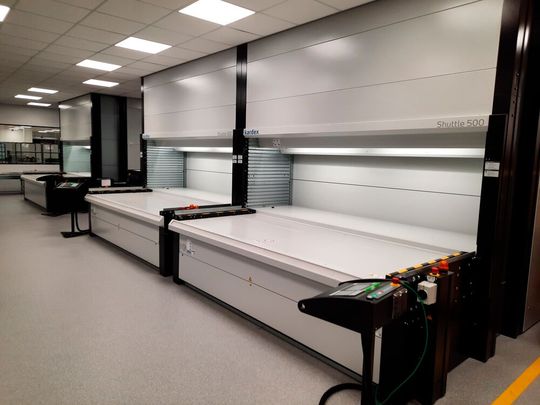 Logber richtete den Materialfluss von EA Elektro-Automatik komplett neu aus und konzipierte in unmittelbarer Nachbarschaft der Fertigungslinien ein zentrales Produktionslager. Lagerlifte helfen nun bei der ergonomischen Kommissionierung von Klein- und Schwerlastteilen. (Bild:  Logber)