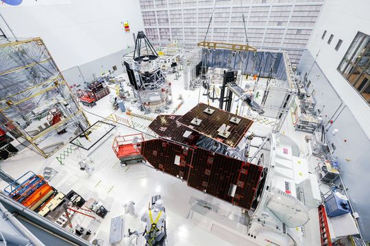 Technicians install solar panels on the exterior of the observatory. The inner part of the telescope is visible in the background, slightly to the left of the center of the image.(Source:  NASA/Sydney Rohde)