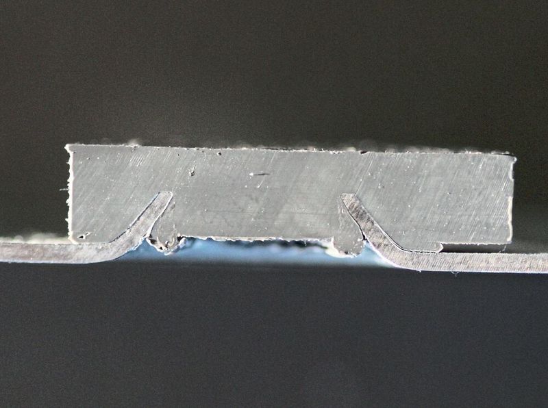 Hier ein Querschnitt einer Fügesituation per Variante Transwwerse, wobei die Befestigung eines Polymerartikels auf einer Blechoberfläche gezeigt wird. (KVT-Fastening)