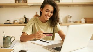 stylish-pretty-student-girl-surfing-internet-in-kitchen-sitting-at-table-with-open-laptop-and-mug-holding-plastic-credit-card-entering-information-via-paying-system-while-shopping-online-stockpack-adobe-stock-scaled (Quelle: shurkin_son-Adobe Stock)