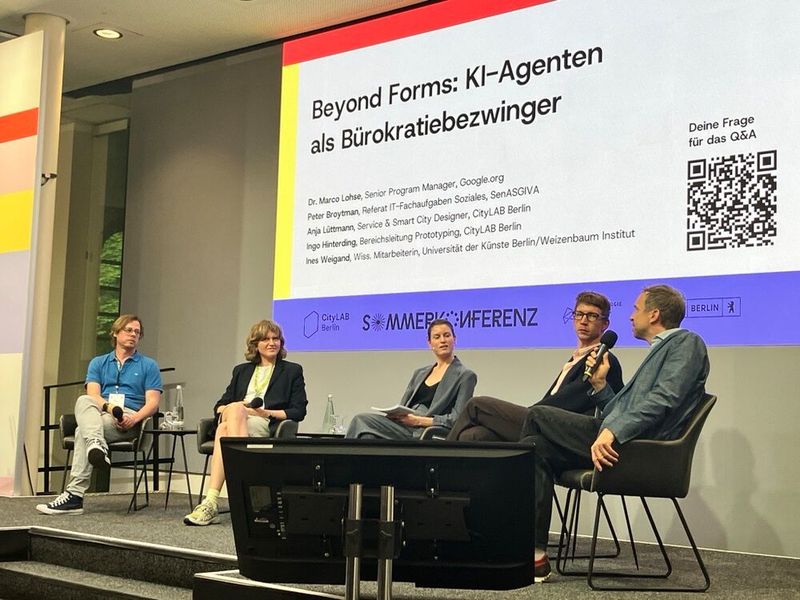 „KI-Agenten als Bürokratiebezwinger“: Auf dem Panel diskutierten Ingo Hinterding, Bereichsleiter Prototyping am CityLAB (v. l. ), und Anja Lüttmann, Service- und Smart-City-Designerin am CityLAB, mit Peter Broytman vom Referat IT-Fachaufgaben Soziales in der Senatsverwaltung für Arbeit, Soziales, Gleichstellung, Integration, Vielfalt und Antidiskriminierung (SenASGIVA) und Dr. Marco Lohse, Senior Program Manager bei Google.org. Moderiert wurde die Runde von Ines Weigand. (Bild: © Serina Sonsalla)