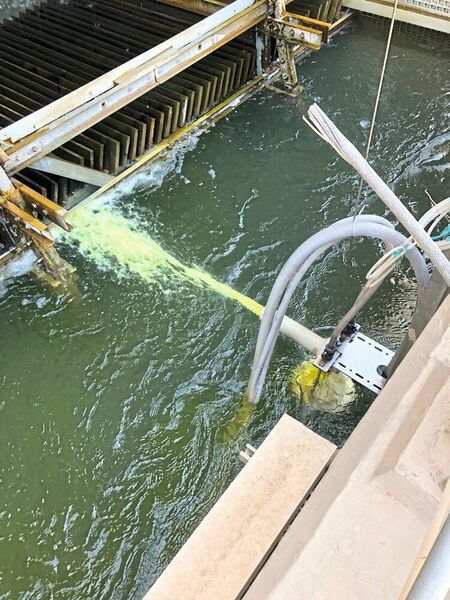 Im Reaktor erzeugtes Biozid wird über einen Kühlwasserstrom ins Kühlwasserbecken geleitet. Klar erkennbar ist die gelblich-grüne Färbung des Wasserstroms, die vom Chlordioxid herrührt. Zu Demonstrationszwecken befindet sich der Reaktor in dieser Abbildung über der Wasseroberfläche, im laufenden Betrieb darunter. (MPT)