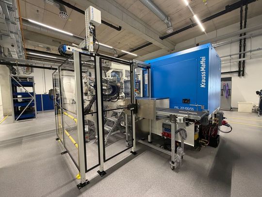 Blick auf die kompakte Produktionszelle mit Entnahmehandling und Förderband der PXL 201-100/55 am Standort Waldkraiburg. (Bild:  Krauss-Maffei)