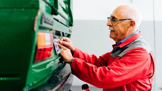 Fast wie vor 30 Jahren: Prüfingenieur Egon Schäfer vergibt eine Prüfplakette nach bestandener Hauptuntersuchung.(Bild:  GTÜ)