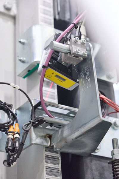 Gesteuert werden die RBGs über Sicherheits-Barcode-Positioniersysteme FBPS 600i von Leuze. An jedem RBG sind zwei Geräte installiert: Eines zur Positionierung der Hubachse – es erfasst die Codes, die auf einem vertikal am RBG angebrachten Barcodeband aufgedruckt sind. Ein weiteres ermittelt die horizontale Position entlang der Fahrachse. (Bild: Leuze)