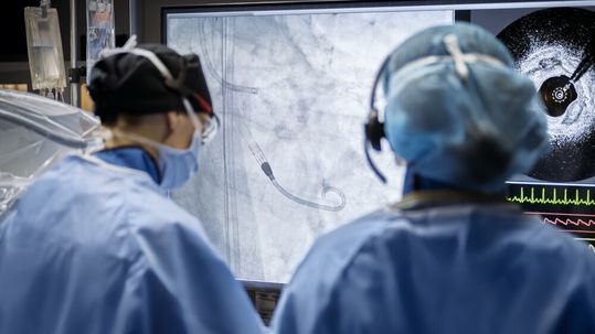 Ein Behandlungsteam verfolgt die Lage der Impella-Pumpe auf dem Durchleuchtungs-bild. Die Pumpe wird unter Röntgenkontrolle über die Aortenklappe in die linke Herzkammer geschoben.(Bild:  Johnson und Johnson)