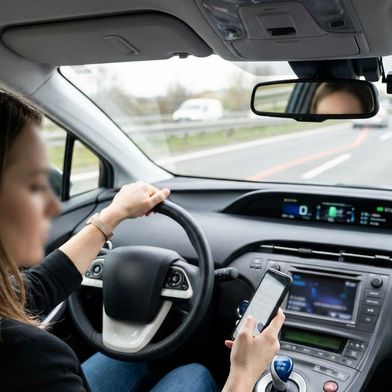 Viele Autofahrer lassen sich von Bildschirmen und Mobiltelefonen ablenken. Die heute üblichen Warnungen der Fahrzeuge greifen zu kurz, lautet das Urteil mehrerer Experten. (Bild: KI-generiert / Gemini)