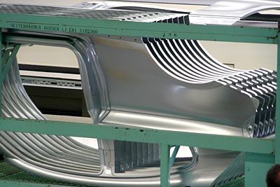 Die Arbeiter am Pressenauslauf nehmen die fertig geformten Seitenteile von Hand auf und stapeln sie zum Weitertransport in die angeschlossene Türen- und Klappenfertigung in entsprechende Transportboxen. (Archiv: Vogel Business Media)