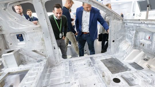 Leichtbau zum Anfassen: Fachbesucher begutachten eine Aluminium-Karosserie auf der ALUMINIUM 2024 (Bild:  Wachenfeld)