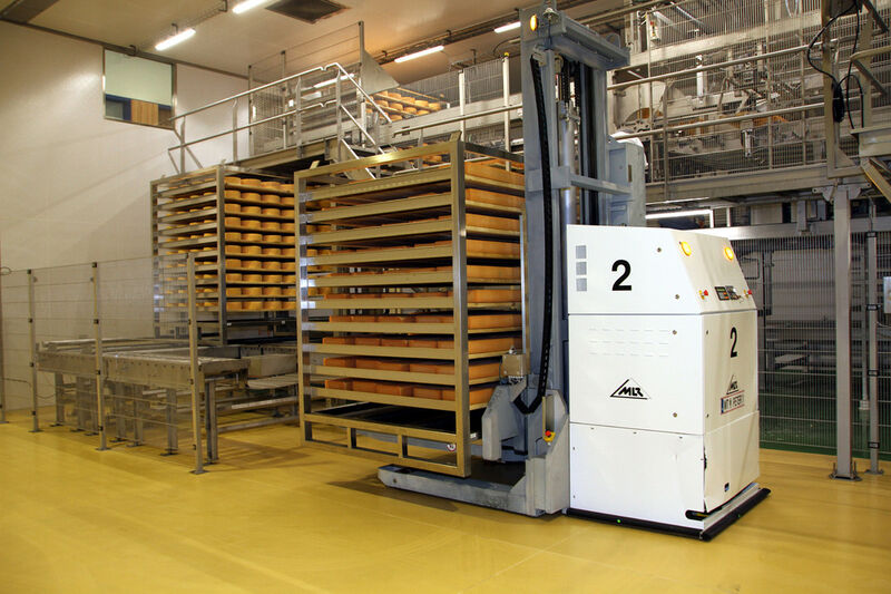Vor der Käsepflegemaschine werden die Gestelle auf eine Zufuhrförderstrecke gesetzt. (Bild: MLR-Gruppe)
