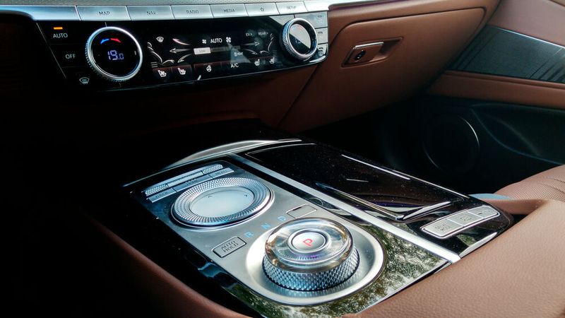 4. Die Dreh-Drücksteller: Die Fahrzeugeinstellungen sind per Sprachsteuerung, Touchscreen oder Dreh-Drücksteller steuerbar. Der Steller fällt recht groß aus und beherrscht Wisch-Gesten. Aber: Er ist zu flach. Zwar ist der Rand mit einer rauen Oberfläche versehen – besser wäre aber ein erhabener Steller, der sich seitlich greifen lässt. Der Wahlschalter für die Fahrstufe lässt sich deutlich besser bedienen. (Bild: Thomas Günnel/Automobil Industrie)