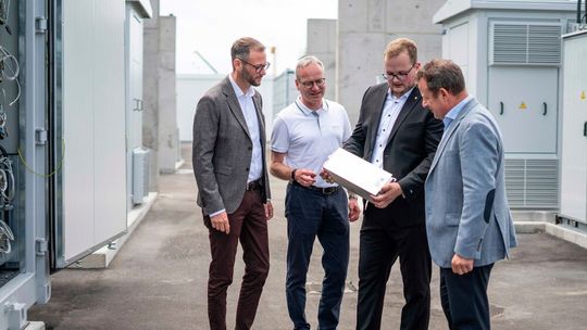 Eines von rund 4.400 Batteriemodulen im Speicher in Leipzig: V.l.: Ruven Weichert, Kaufmännischer Geschäftsführer Porsche Leipzig GmbH; Alwin Schmid, Leiter Fachgebiet Elektrotechnik Porsche AG; Jonathan Dietrich, Projektleiter Porsche AG Batteriespeicher Werk Leipzig; und Gerd Rupp, Vorsitzender der Geschäftsführung der Porsche Leipzig GmbH.(Bild:  Porsche)