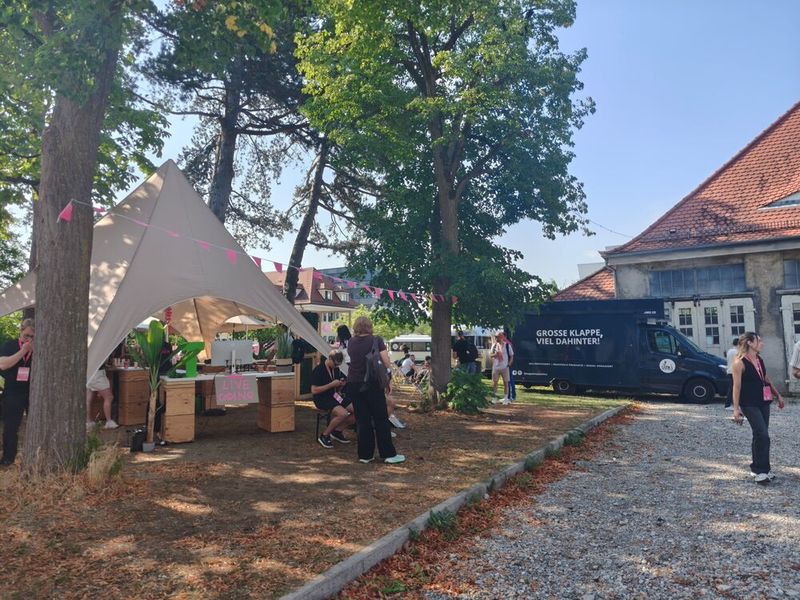 Live-Musik, Foodtrucks, Sonnenstühle und schnell vergriffene Eiscreme: Die Sparkscon vereint Digitalisierungsthemen mit sommerlichem Festivalflair auf dem historischen Gaswerksgelände in Augsburg. Am 17. Juli 2026 kamen rund 2.000 Besucherinnen und Besucher sowie mehr als 70 Speaker zusammen. (Bild: © Serina Sonsalla)