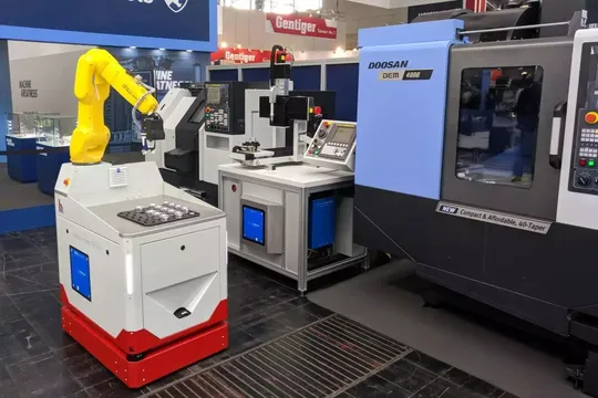 Nahtlose Integration: Ein mit einem Roboterarm ausgestattetes fahrerloses Transportsystem nutzt die Prozesszeit an der Bearbeitungsstation für das kabellose Laden (In-Process-Charging), was zusätzliche Ladestopps überflüssig macht.(Bild:  Wiferion)