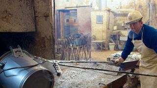 Auf der einen Seite des Beckens steht ein Mann mit einer bodenlangen Gummischürze. In den Händen hat er eine über 2 m lange Spezialzange, mit der er einen Blecheimer in eine gräuliche Flüssigkeit taucht, tief ins Becken drückt und weit nach vorne schiebt. (Bild: Gesamtmetall/Pit Junker)