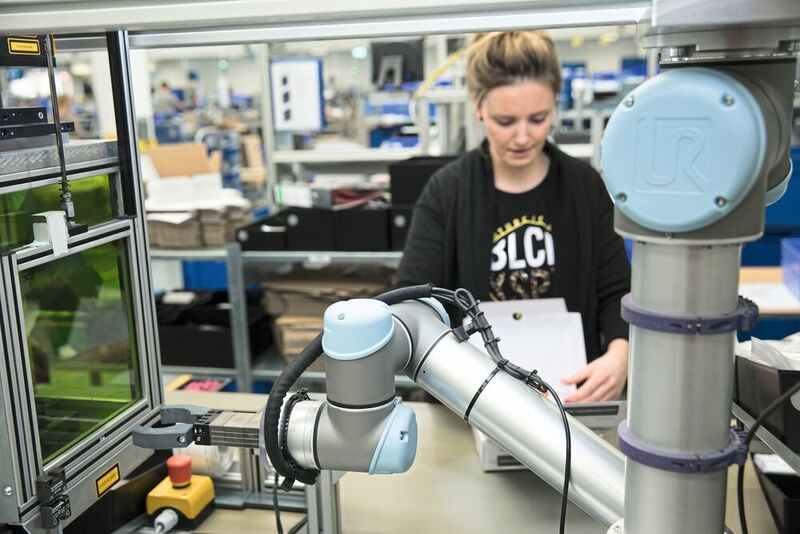 Kollaborierende Roboter schaffen keine Arbeitsplätze ab, sondern entlasten den Menschen bei seinen Tätigkeiten. Bei Jung bilden der UR5 und seine Bedienerin ein eingespieltes Team.  (Universal Robots)