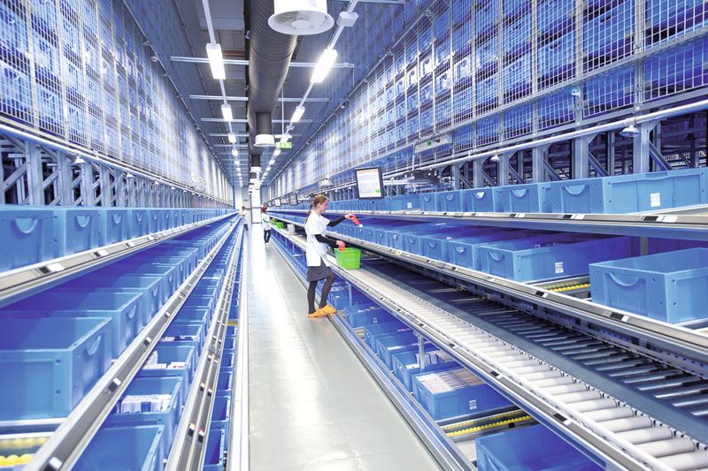 Im Distributionszentrum von Salus entnehmen die Mitarbeiter, geführt von integrierten Pick-by-Light-Systemen, die entsprechenden Auftragsposten und kommissionieren sie direkt in die Versandbehälter. (Bild: SSI Schäfer)