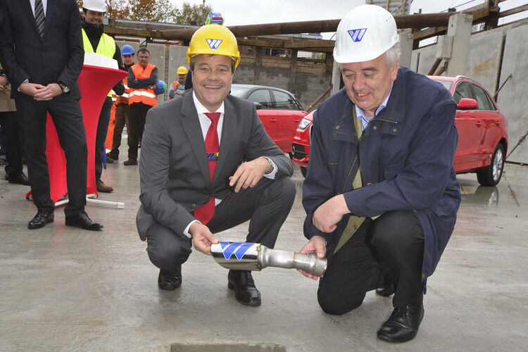 Bernd Glathe und Bernd Kußmaul, Geschäftsführer von Auto Wichert bei der Grundsteinlegung mit einem Audi-Q7-Auspuffrohr als Zeitkapsel. (Foto: Wichert)