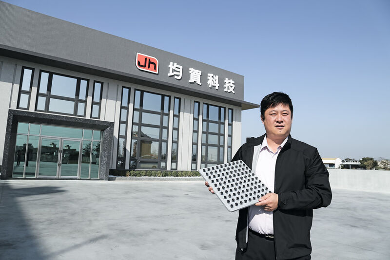 CEO Wang Jiang-Quan vor dem Hauptsitz von Jun He, in den Händen eine Palette mit Kunstoffgehäusen für Smartphone-Kameralinsen. (Bild: Zeiss)