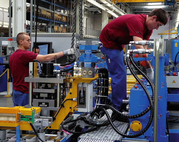 Während der eine Mechaniker die Versorgungsleitungen abklemmt, ist der zweite dabei, die zu wechselnde Stanzeinheit bereits an einen Kranhaken zu hängen. (Bild: Kuhn)