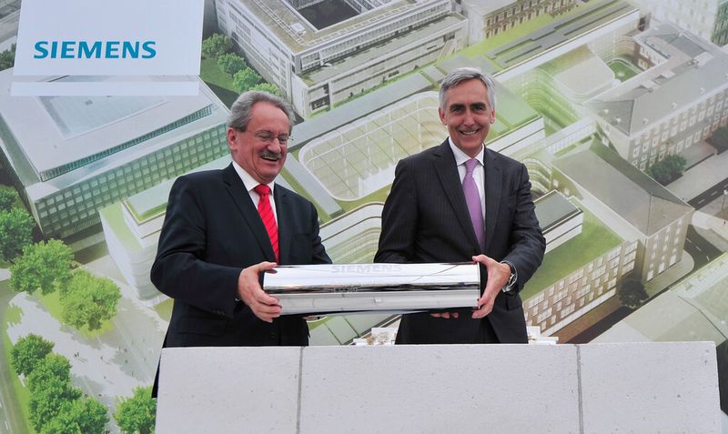 Für den Grundstein wird traditionell eine Zeitkapsel mit aktuellen Beigaben, Dokumenten, und Münzen gefüllt. Münchens Oberbürgermeister Christian Ude und Siemens Chef Peter Löscher legen die Zeitkapsel in den Grundstein. (Siemens/Lennart Preiss)