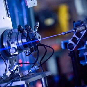 Der extrem intensive Röntgenstrahl regt den Stickstoff in der Luft zum Leuchten an, wenn die Moleküle seinen Weg kreuzen. Trotz der extrem hohen Intensität des Strahls ist das Leuchten des Stickstoffs vergleichsweise schwach und wäre mit bloßem Auge nicht so leicht zu erkennen. So deutlich sichtbar wie auf dem Foto wird der Strahl erst bei völliger Dunkelheit und einer Belichtungszeit von 90 Sekunden, aufgenommen an der Experimentierstation FXE.(Bild:  European XFEL / Jan Hosan)