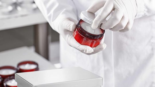 Ein Mitarbeiter füllt bei einem Outsourcing-Partner für große globale Kosmetikmarken und auch für Eigenmarken ein Döschen mit kosmetischer Salbe.(Bild:  Minebea Intec)