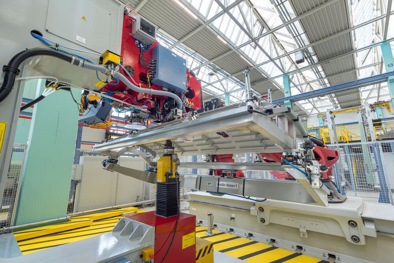 Das Ausrichten der Einzelteile wie Stringer und Clips sowie das Heften der Teilschalen erfolgt manuell, das Bohren, Senken und Niete setzen erfolgt hochautomatisiert. Der Roboter übernimmt das Teilehandling und führt die Baugruppe dem Nietautomat zu. (Premium Aerotec)