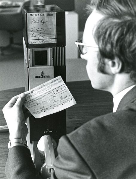 Vision von 1972: Mit dem Zukunftsterminal Bildfernsprecher lässt sich ein höherer Datendialog praktizieren. Auf der Hannover Messe demonstrierte Siemens die Darstellung von Originalunterschriften aus einem mikrographischen Speicher zu Kontrollzwecken im Bankwesen. (Bild:  Siemens)