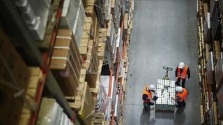 above-view-of-people-working-in-large-warehouse-counting-goods-on-moving-cart-between-shelves-with-packed-boxes-stockpack-adobe-stock-scaled (Quelle: pressmaster-Adobe Stock)